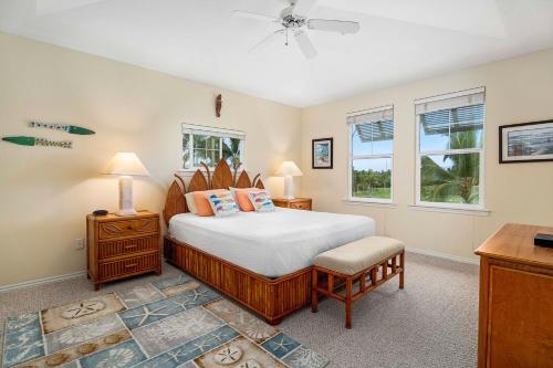a bedroom with a bed and a desk and two windows at Fairway Villas Waikoloa A31 in Waikoloa