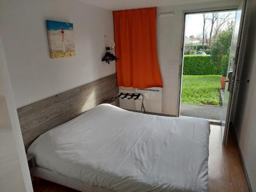 ein Schlafzimmer mit einem Bett und einem Fenster mit einem orangen Vorhang in der Unterkunft Premiere Classe Saintes in Saintes