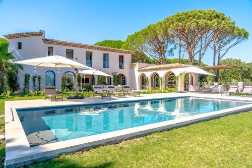 une piscine en face d'une maison avec des parasols dans l'établissement Villa Bagatelle, à Grimaud
