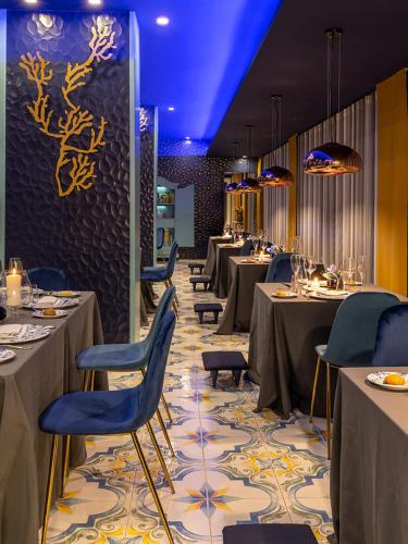 a dining room with tables and chairs and blue chairs at Villa Aragonese Rooms in Monte di Procida