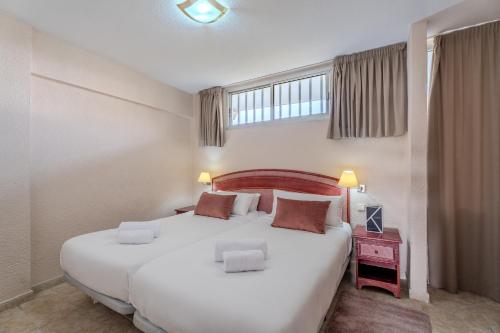 um quarto com uma grande cama branca e uma janela em OBSIDIAN Apartamento Santa María em Adeje