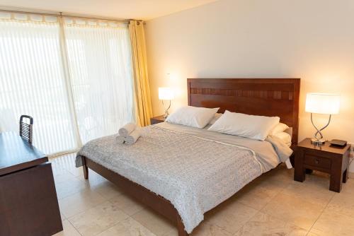 1 dormitorio con 1 cama con 2 lámparas y una ventana en A Star Oasis Condo, en Palm-Eagle Beach