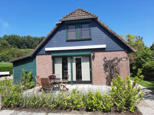una pequeña casa azul con mesa y sillas en Ruime vrijstaande vakantiewoning aan Veerse meer, 6 persoons, en Wolphaartsdijk