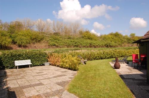 a patio with a bench and a field of grass at Ruime vrijstaande vakantiewoning aan Veerse meer, 6 persoons in Wolphaartsdijk