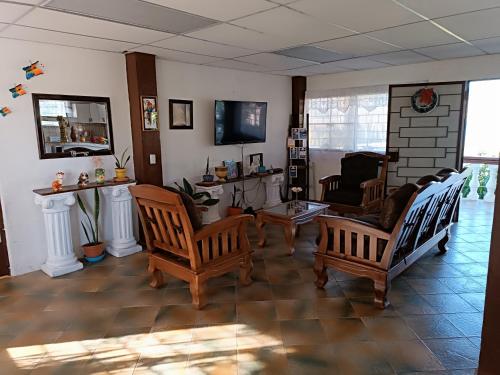 a living room with two chairs and a tv at Quinta El Espino in Ahuachapán