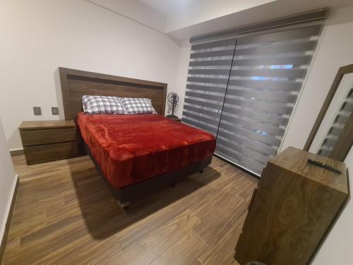1 dormitorio con 1 cama con manta roja en Depa y Alberca a 5 min del auditorio, en Guadalajara