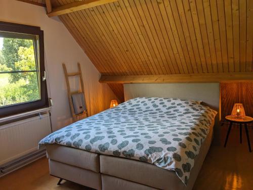 a bedroom with a bed with a wooden ceiling and a window at Ruime vrijstaande vakantiewoning aan Veerse meer, 6 persoons in Wolphaartsdijk