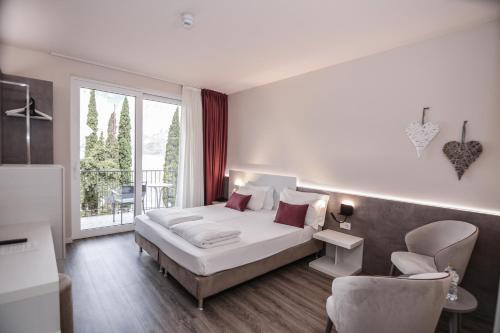 a bedroom with a bed and a large window at Hotel Oasi Beach in Malcesine