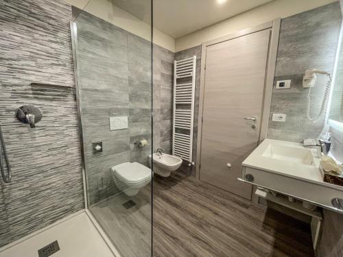 a bathroom with a shower and a toilet and a sink at Hotel Oasi Beach in Malcesine