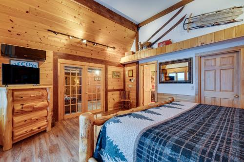 1 dormitorio con 1 cama, TV y paredes de madera en Pittsburg Lake House with Magalloway Mountain Views!, en Pittsburg