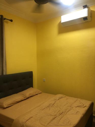a bedroom with a bed with a yellow wall at The Pines Small Studio in Kota Bharu