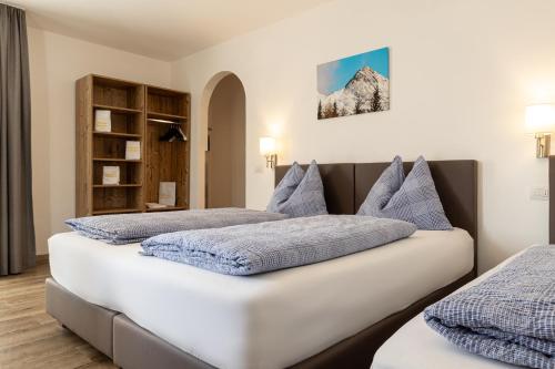 een slaapkamer met 2 bedden en een boekenplank bij B&B Hotel Sonneck in Naz-Sciaves
