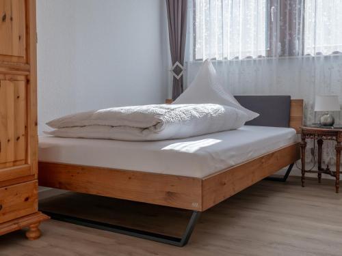 a bed with white sheets and pillows on it at Pension Haus Monika in Sasbachwalden