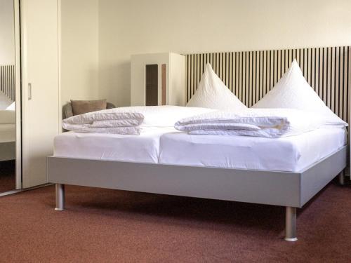 Un dormitorio con una cama blanca con almohadas. en Pension Haus Monika, en Sasbachwalden