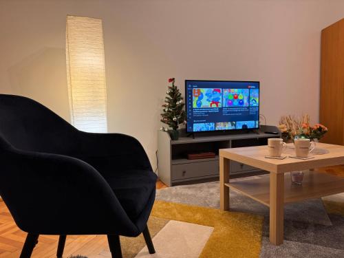 a living room with a black chair and a television at SKY Apartment in Odorheiu Secuiesc