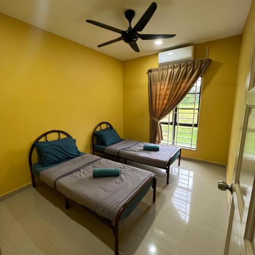 2 łóżka w pokoju z wentylatorem sufitowym w obiekcie D` Totok HouseStay w mieście Sepang