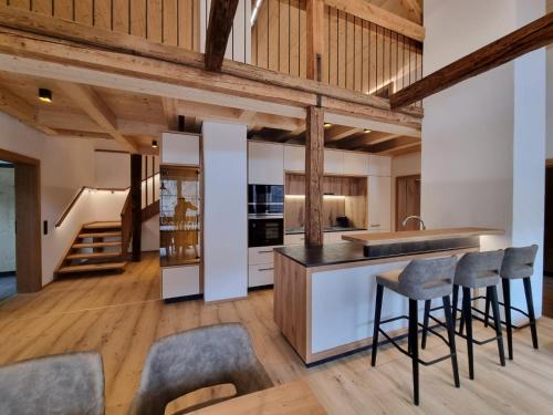 una cucina a pianta aperta con soffitti e sgabelli in legno di das MARX - Gasthof Marx - Apartments a Grosskirchheim