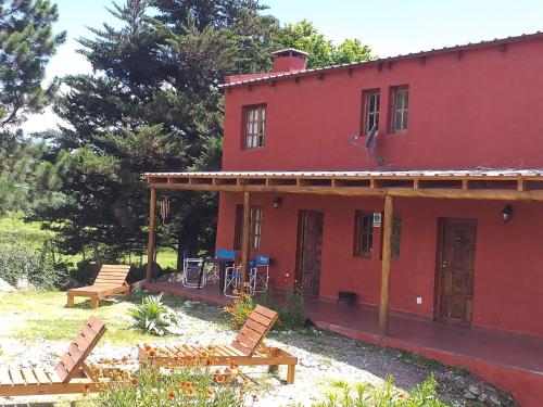 una casa roja con dos bancos delante en PORTAL DE LA OVEJERIA en Tafí del Valle