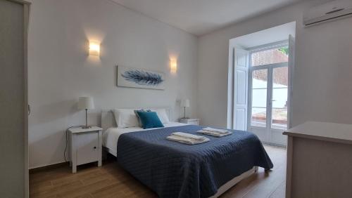 a bedroom with a bed with blue sheets and a window at Lightoasis Oeiras 3 in Oeiras