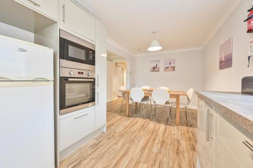 a kitchen with white cabinets and a table with chairs at Superb Sandbanks Apartment near Beach and Bars with Free Parking in Poole