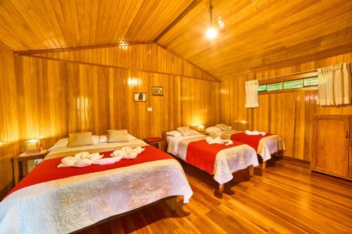 two beds in a room with wooden walls and wood floors at Carolina Egg Gasthaus in Oxapampa