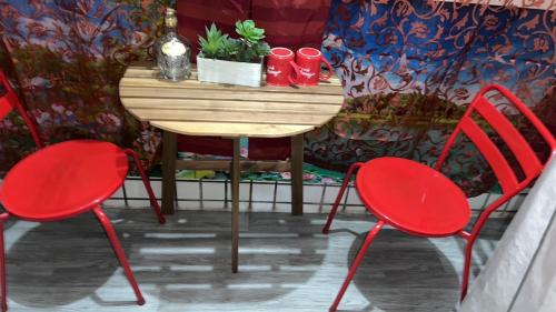 Dos sillas rojas y una mesa con una planta. en Jiajia Inn, en Lukang