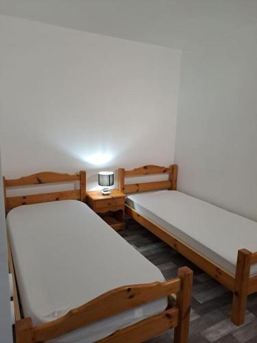 une chambre avec deux lits et une table avec une lampe dans l'établissement Appartement résidence Les Dryades avec vue montagne, à Gérardmer