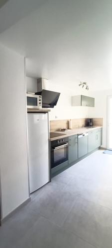 - une cuisine avec des appareils blancs dans une pièce blanche dans l'établissement L'étoile du RDC, à Gravelines