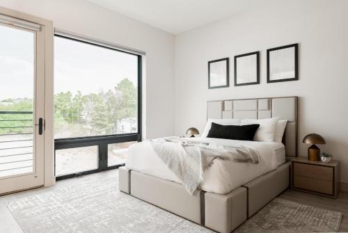 a white bedroom with a bed and a large window at Luxurious Escape - Walk to Empower Field - Tesoro in Denver