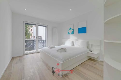 biała sypialnia z białym łóżkiem i oknem w obiekcie Home Sofia Room 2 - Modern Station -By EasyLife Swiss w mieście Lugano
