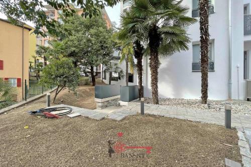 a yard with a boat and a bench and palm trees at Home Sofia Room 2 - Modern Station -By EasyLife Swiss in Lugano