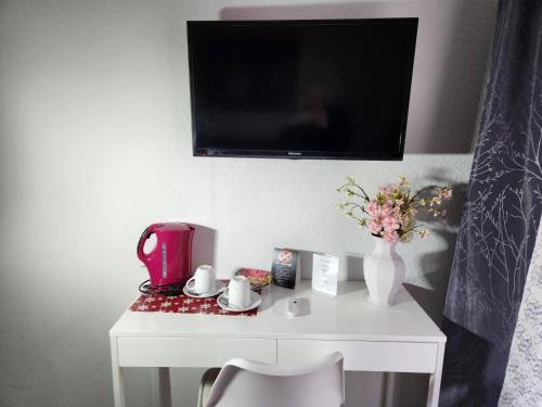 mesa blanca con cafetera y TV en la pared en City Hotel - Doppelzimmer en Rastatt