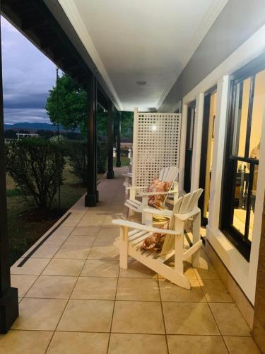 a porch with two white chairs on a house at KarMichael Farm in Himeville