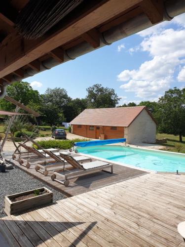 a swimming pool with a wooden deck and a building at Le Petit Pré in Bouesse