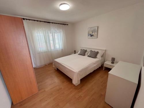 a bedroom with a white bed and a window at Apartmani Pavlović in Sućuraj