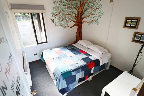 a bedroom with a tree mural on the wall at Punto Rockstar Osorno in Osorno