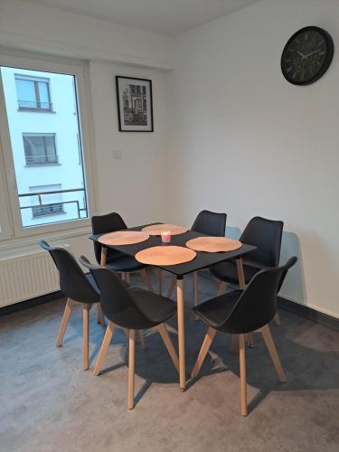 une table et des chaises dans une pièce avec une horloge au mur dans l'établissement Appartement 3 pièces faubourg de Pierre, à Strasbourg