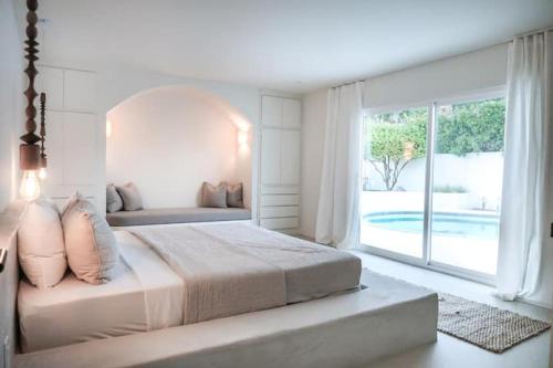 - une chambre blanche avec un grand lit et une grande fenêtre dans l'établissement Luxury Desert Retreat with Pool & Mountain View, à Palm Springs