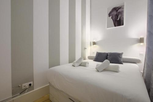 een witte slaapkamer met een wit bed met 2 kussens bij Charming Madrid Embajadores - Estancias Temporales in Madrid