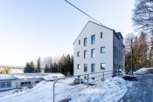 a white building with snow on the ground at Apartmány u Sjezdovky in Pernink