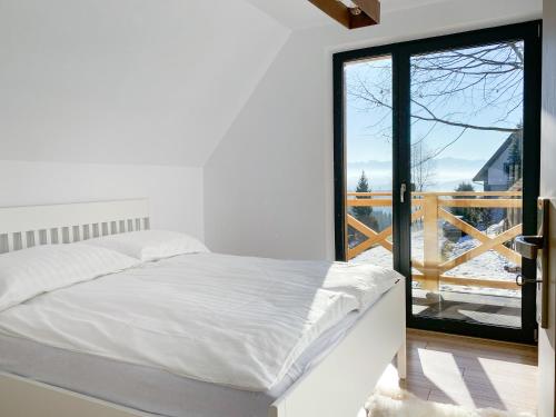 a bedroom with a white bed and a large window at Jankówki - Dom w górach in Nowy Targ