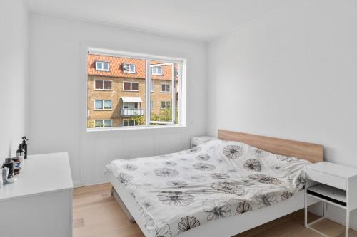 a white bedroom with a bed and a window at Modern Central Located Apartment in Copenhagen