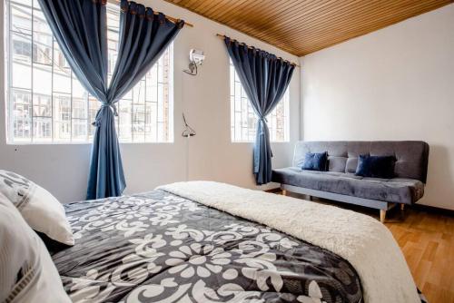 a bedroom with blue curtains and a bed and a couch at Samor centro histórico Bogota in Bogotá