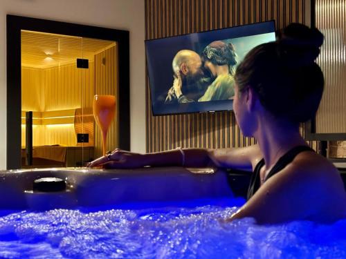 a woman sitting in a hot tub in a room at Jacuzzi Loft & Sauna Sanctuary in Katowice