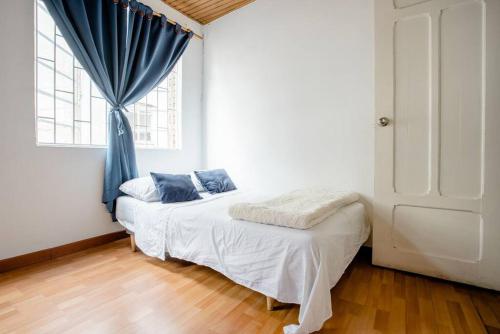 a bedroom with a bed with a blue curtain and a window at Samor centro histórico Bogota in Bogotá