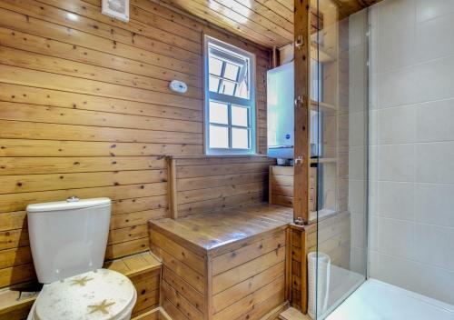 a wooden bathroom with a toilet and a shower at Bosuns Cottage in Torquay