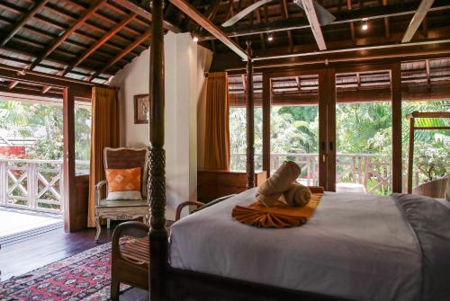 a bedroom with a bed and a chair and windows at Villa Hangat in Seminyak