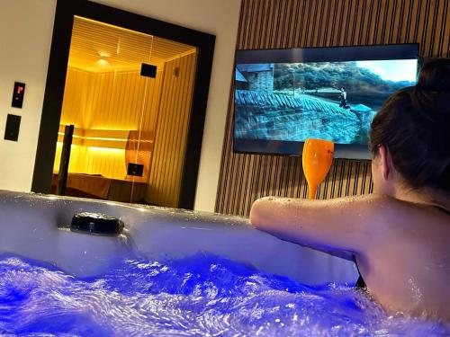 a man in a bathtub with a tv in a room at Jacuzzi Loft & Sauna Sanctuary in Katowice