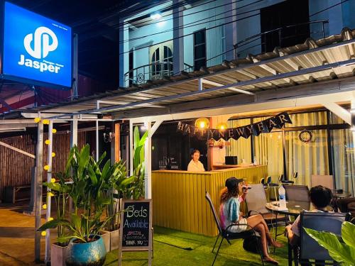 un grupo de personas sentadas fuera de un restaurante por la noche en Jasper Phangan Hostel, en Thong Sala