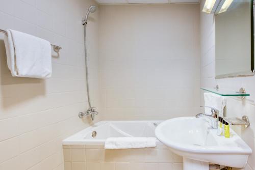 a white bathroom with a sink and a bath tub at Elite LUX Holiday Homes - Fabulous Studio in Dubai Marina in Dubai